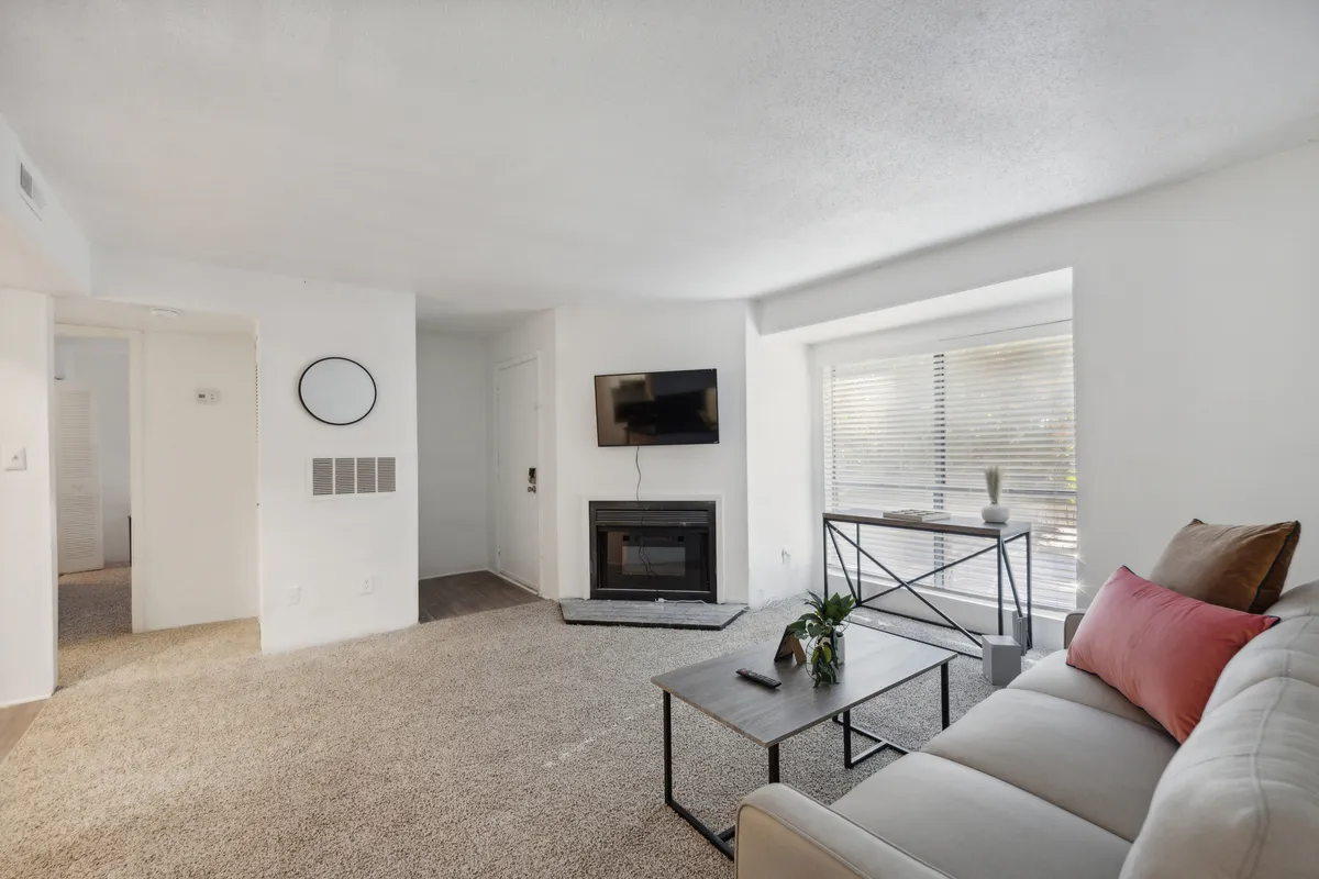 A spacious, light-filled living room featuring a modern sofa, fireplace, TV, and coffee table. The setting is both welcoming and functional, ideal for relaxing after a day of settling in or entertaining new neighbors. The room exudes comfort with sunlight streaming in, highlighting the organized, ready-to-live-in space.