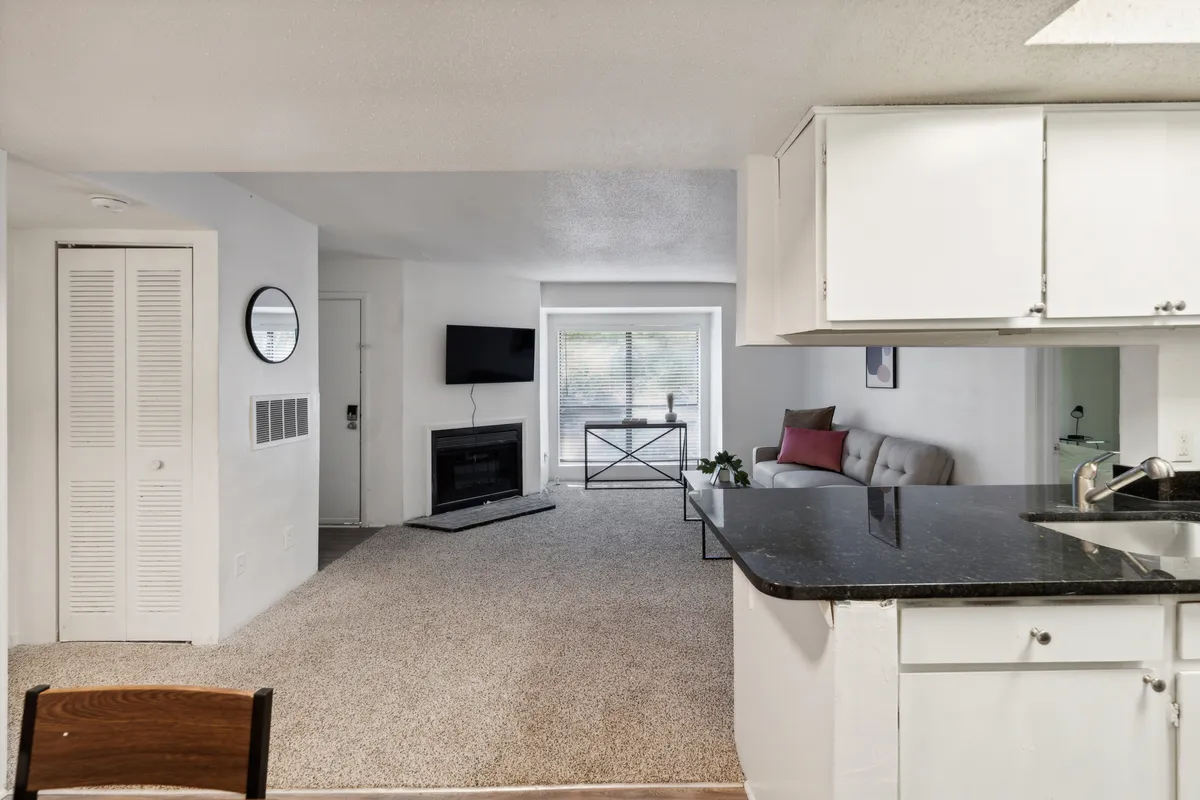 A cozy living room scene featuring a fireplace, sofa, and dining table, staged for both relaxation and entertaining. The view invites guests to imagine returning after exploring local eateries and boutiques, settling in for a relaxing evening.